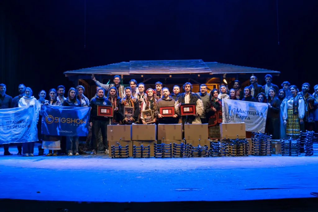 Група людей на сцені з прапорами та нагородами