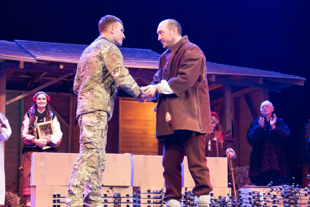 Військовий тисне руку чоловіку на сцені