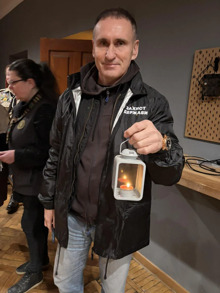 Чоловік тримає ліхтар із запаленою свічкою