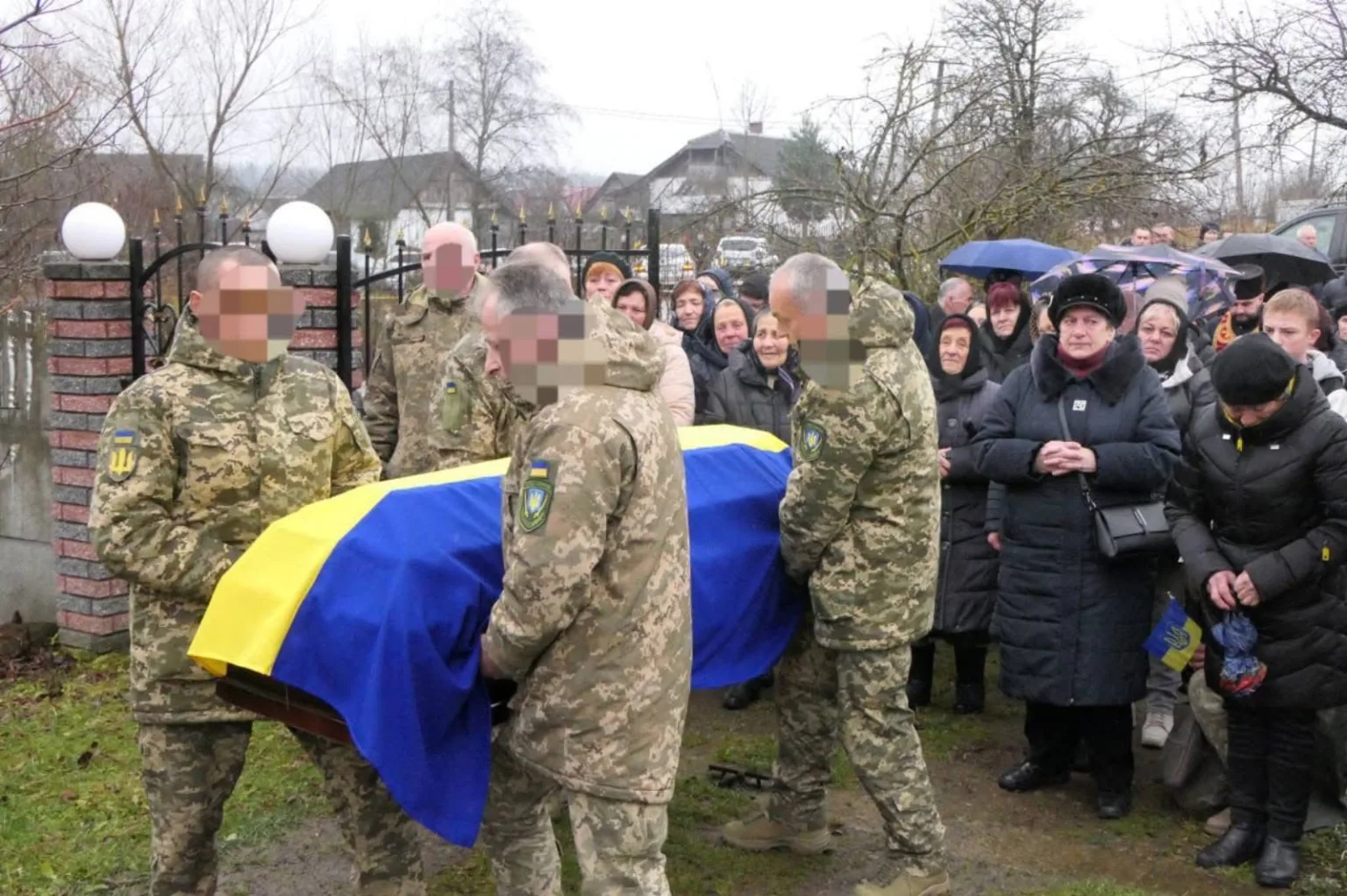 Військові несуть труну, вкриту українським прапором
