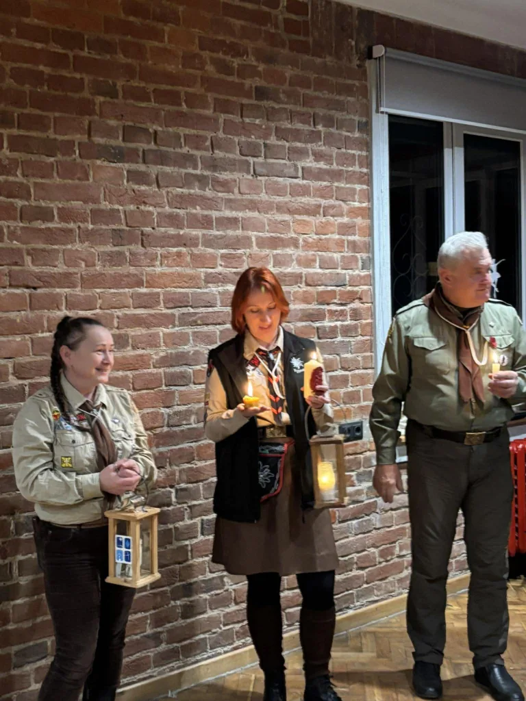 Скаути тримають ліхтарі зі свічками біля цегляної стіни