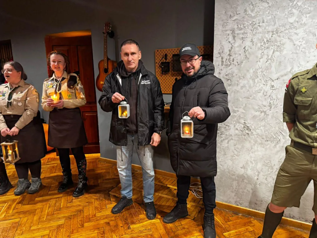 Люди тримають ліхтарі з вогнем у приміщенні