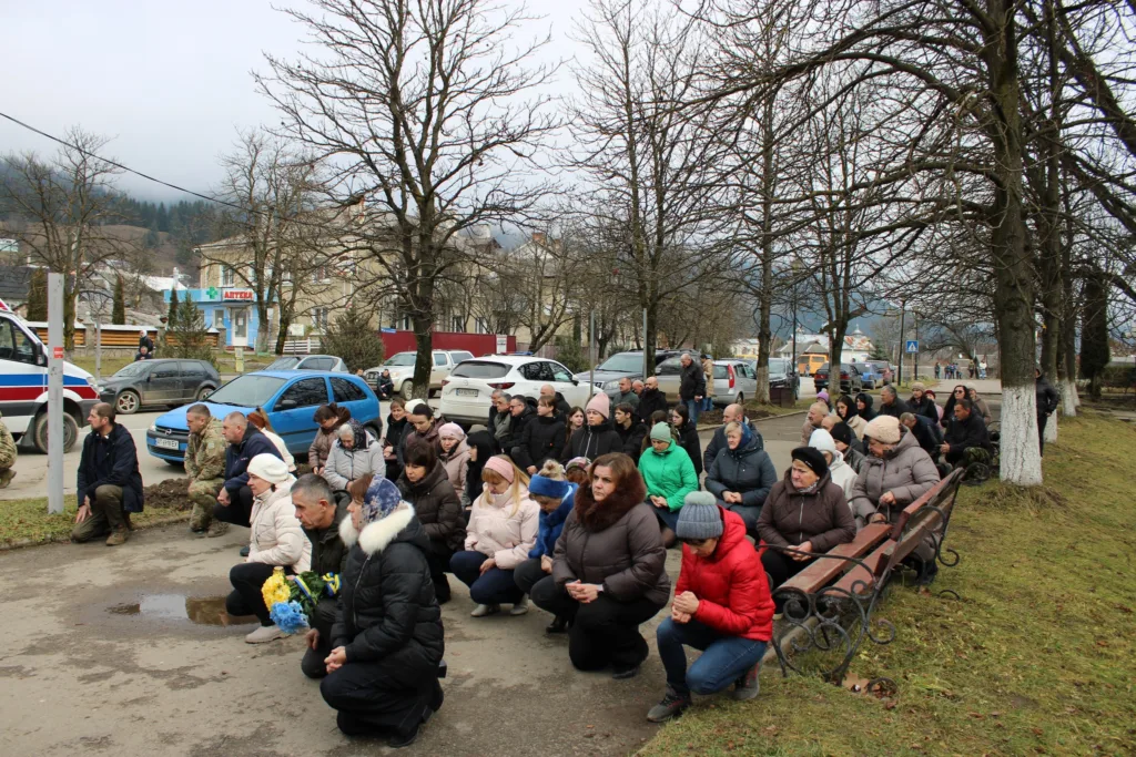 Люди стоять на колінах під час вшанування героїв