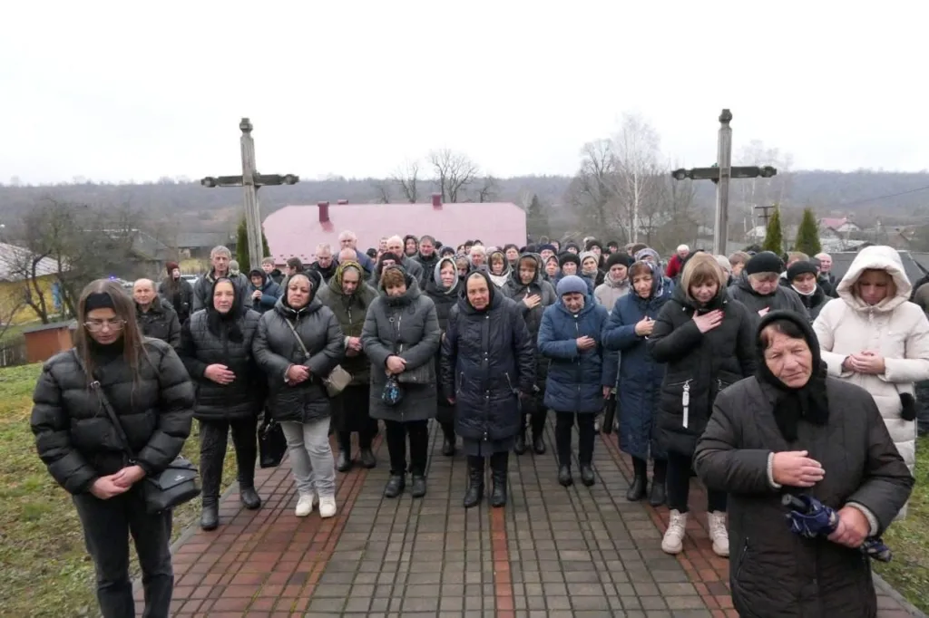 Люди стоять біля хреста, вшанування пам'яті.
