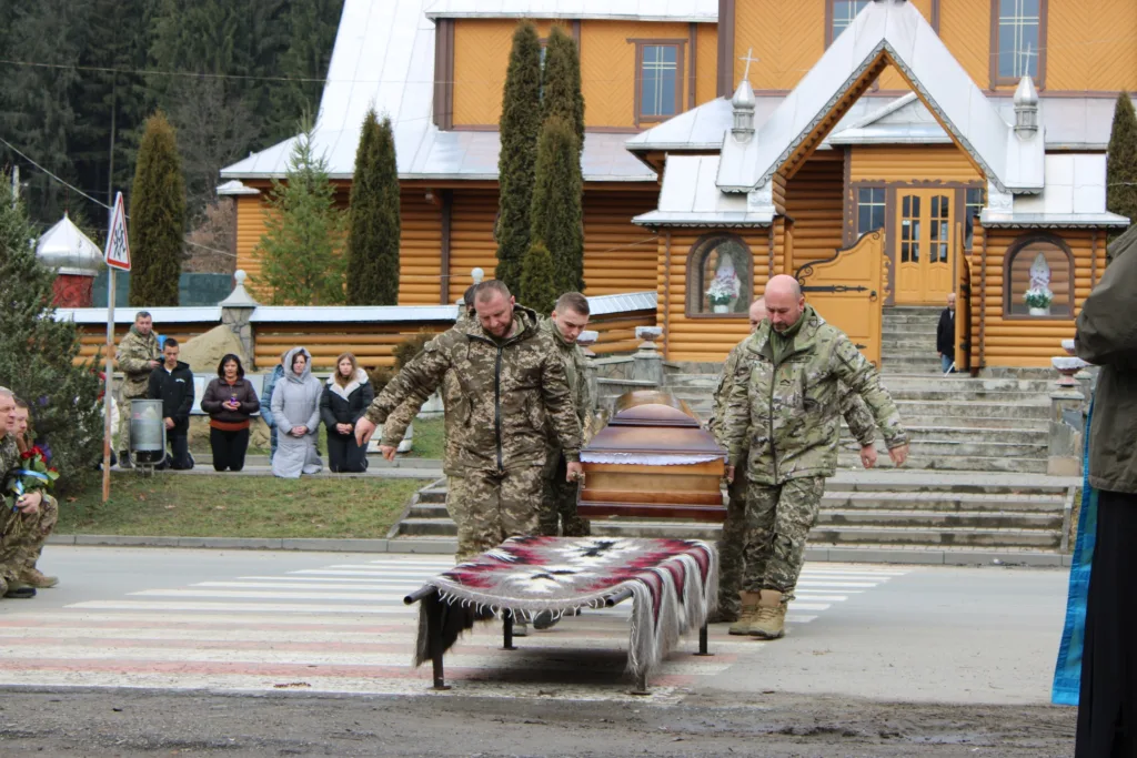 Військові несуть труну перед церквою