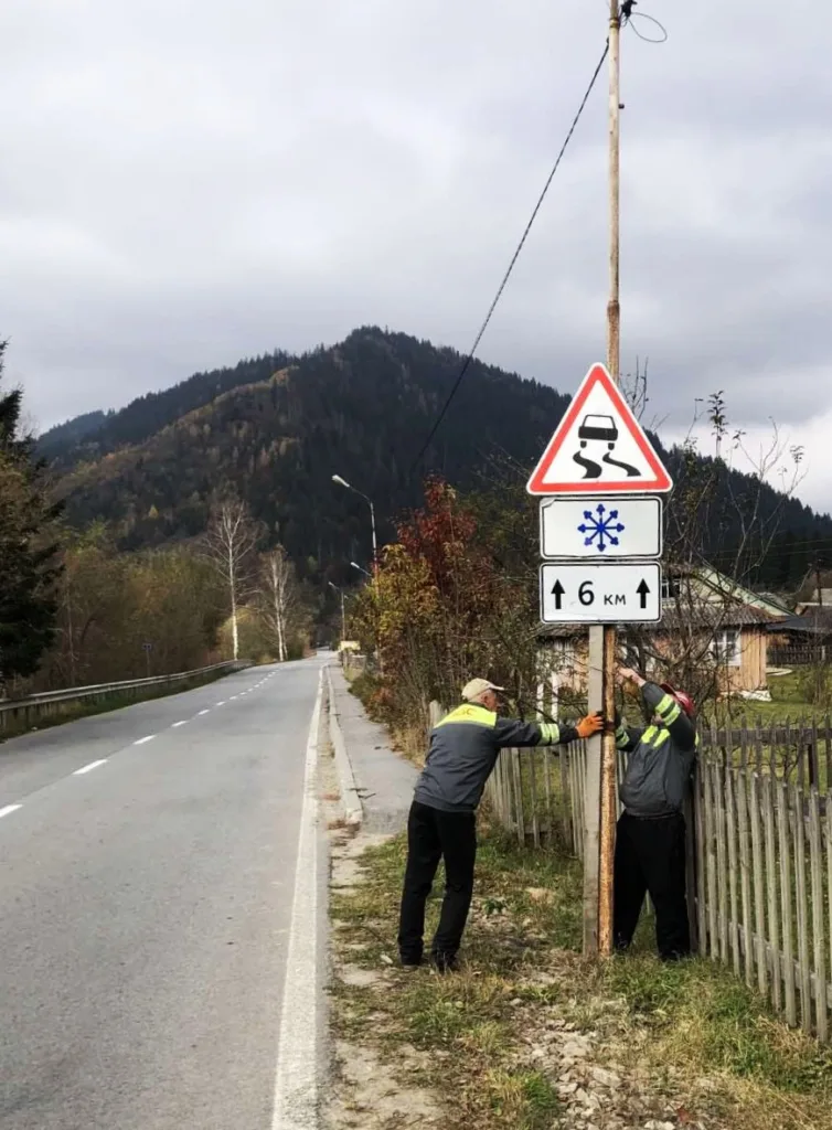 Робітники встановлюють дорожній знак у горах