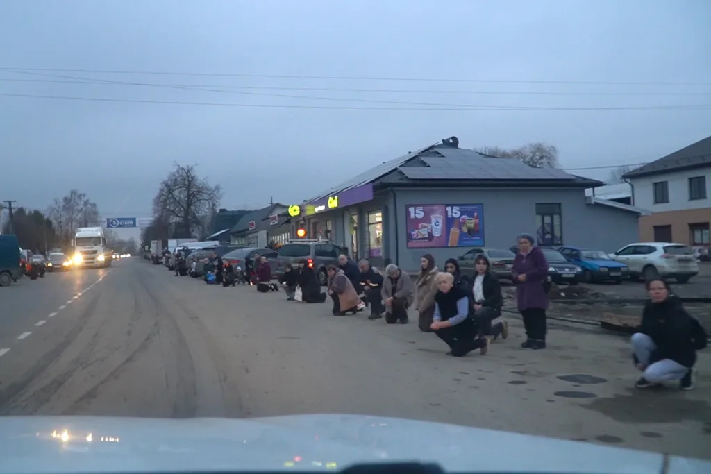 Люди стоять на колінах уздовж дороги