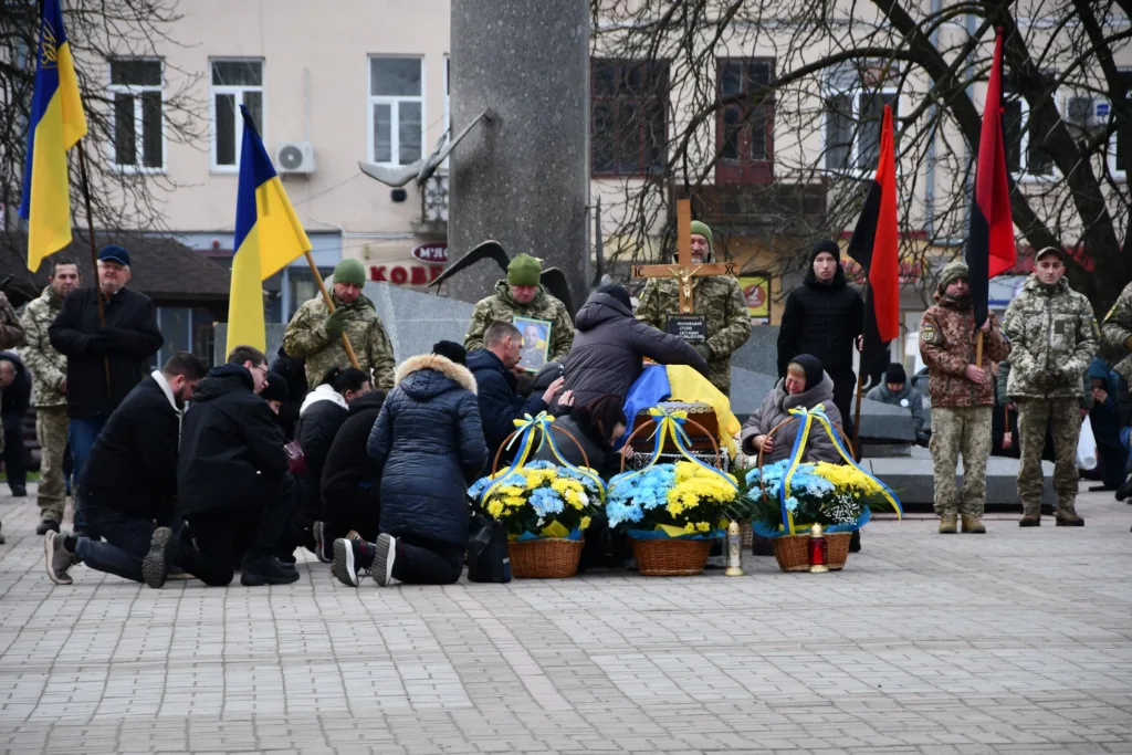 Вшанування загиблого воїна з українськими прапорами