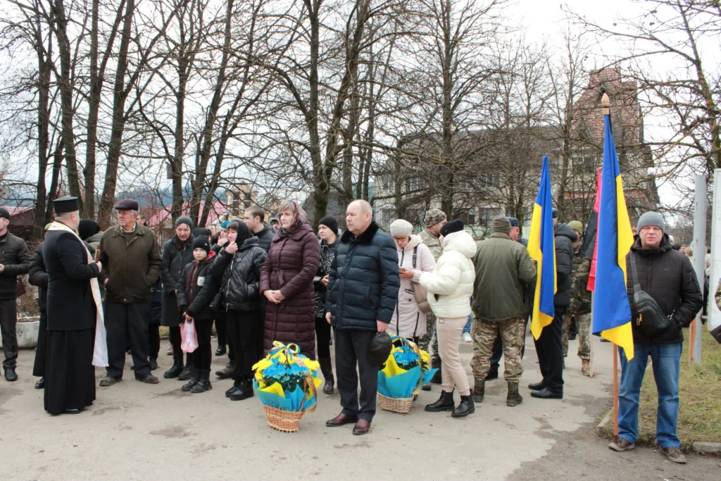 Люди з українськими прапорами на вуличній церемонії
