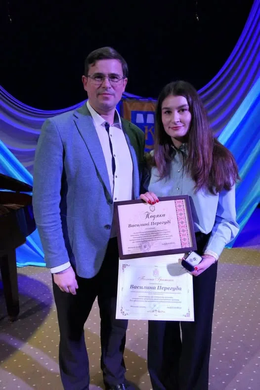 Двоє людей отримують нагороду на сцені