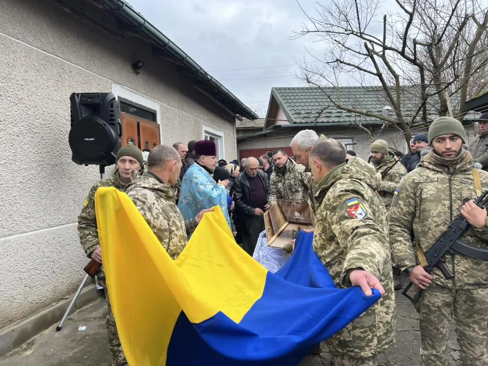 Військові проводжають героя з українським прапором
