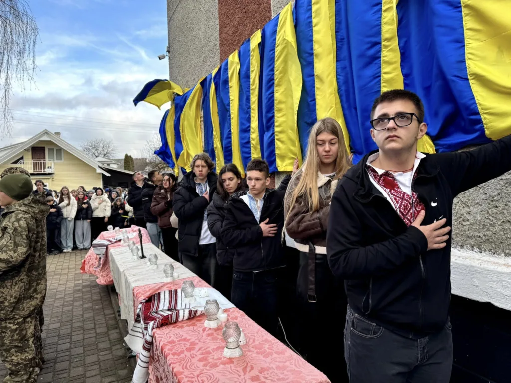 Люди стоять біля прапора України під час церемонії