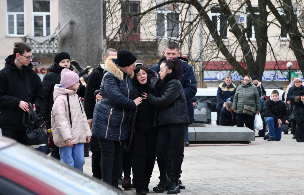 Люди підтримують заплакану жінку на вулиці міста
