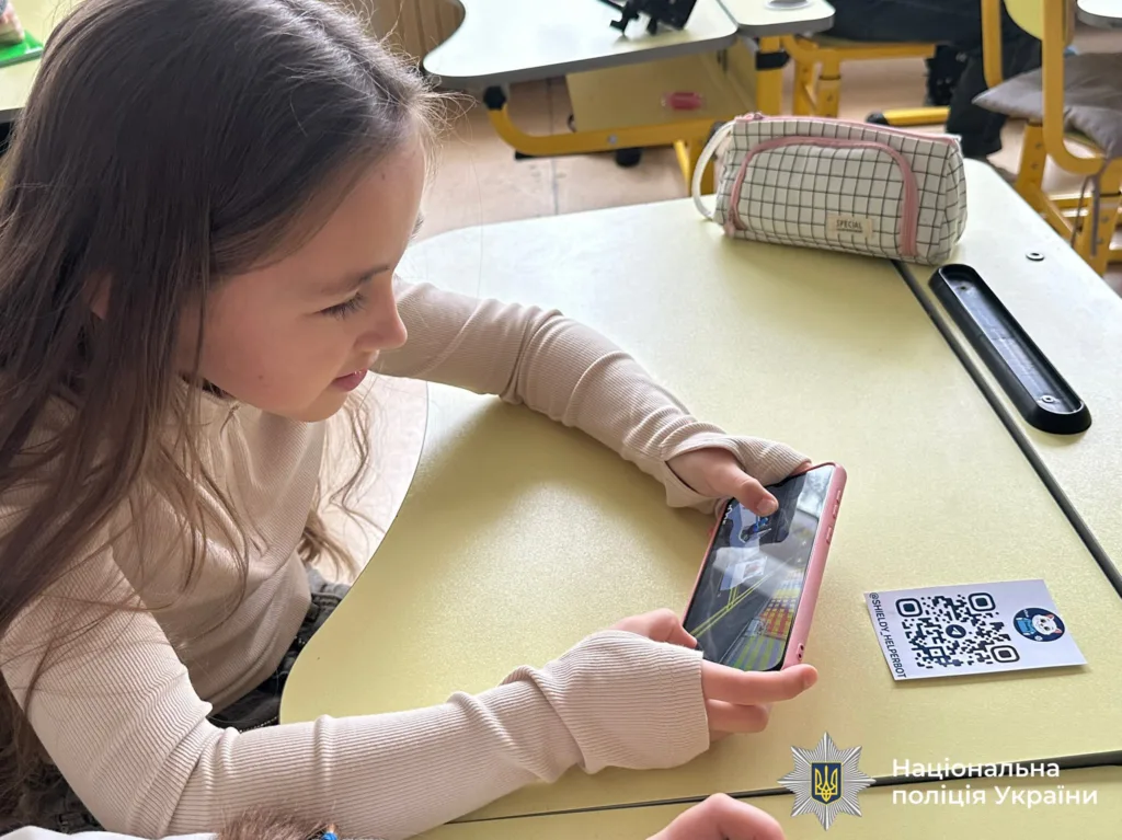 Дитина грає на смартфоні в класі