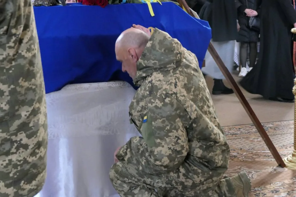 Військовий прощається з побратимом, накритим прапором України