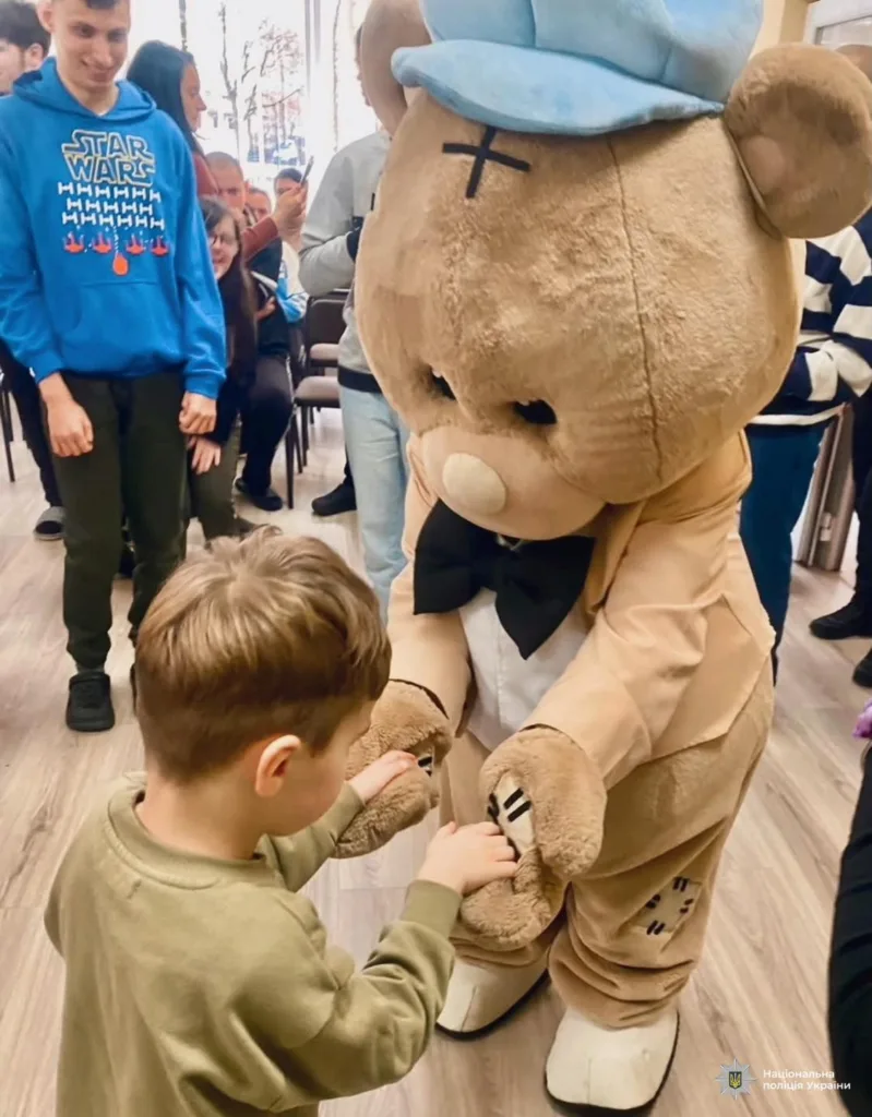 Дитина вітається з людиною у костюмі ведмедя