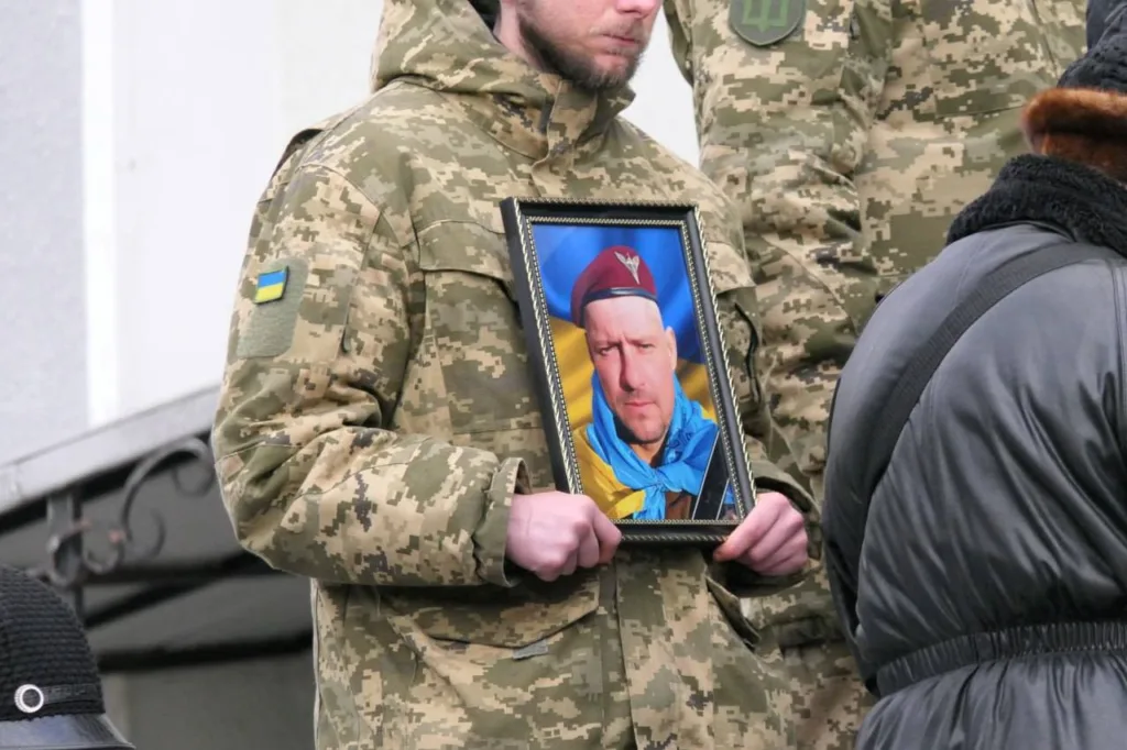 Військовий тримає портрет загиблого захисника України