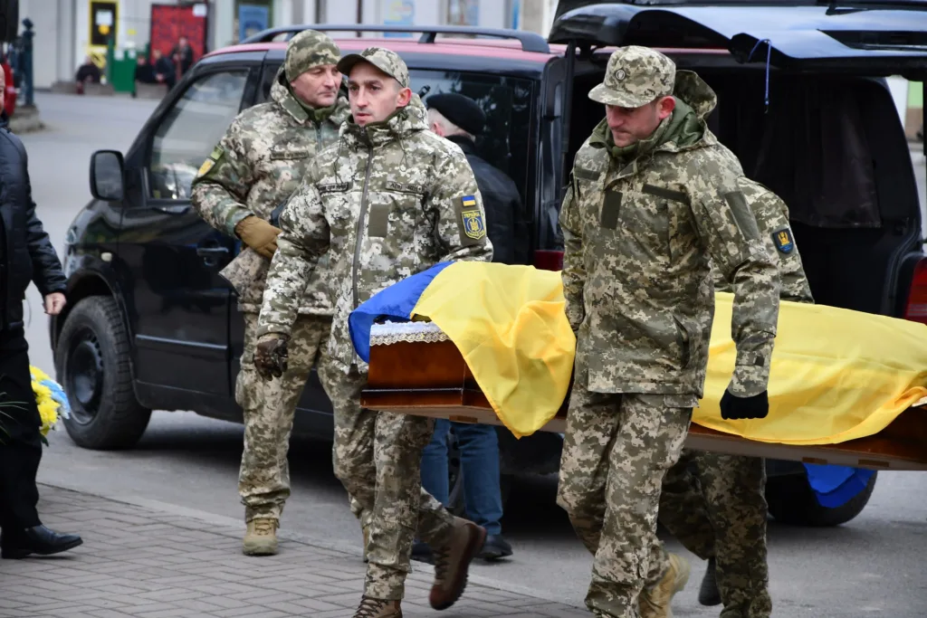 Військові несуть труну, накриту прапором України