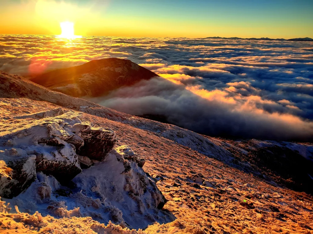 Сонячний схід над засніженими горами і хмарами