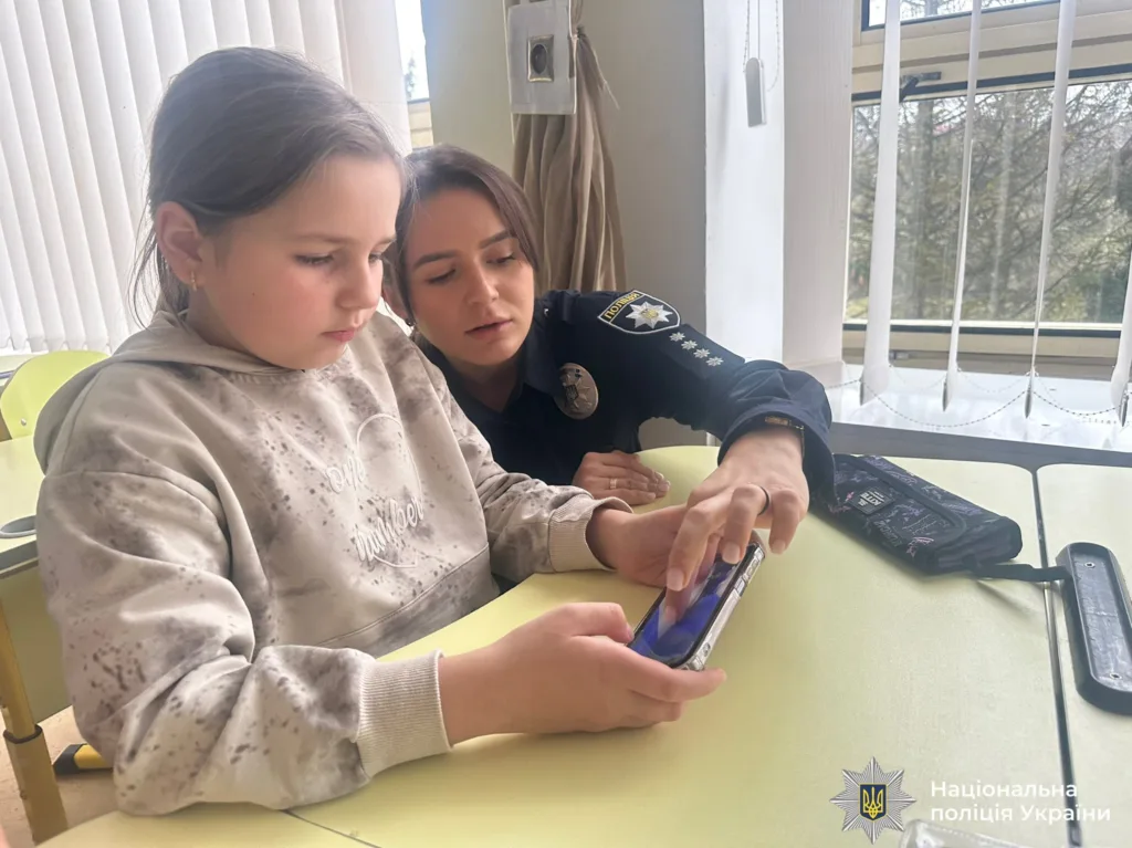 Поліцейська допомагає дівчинці з телефоном