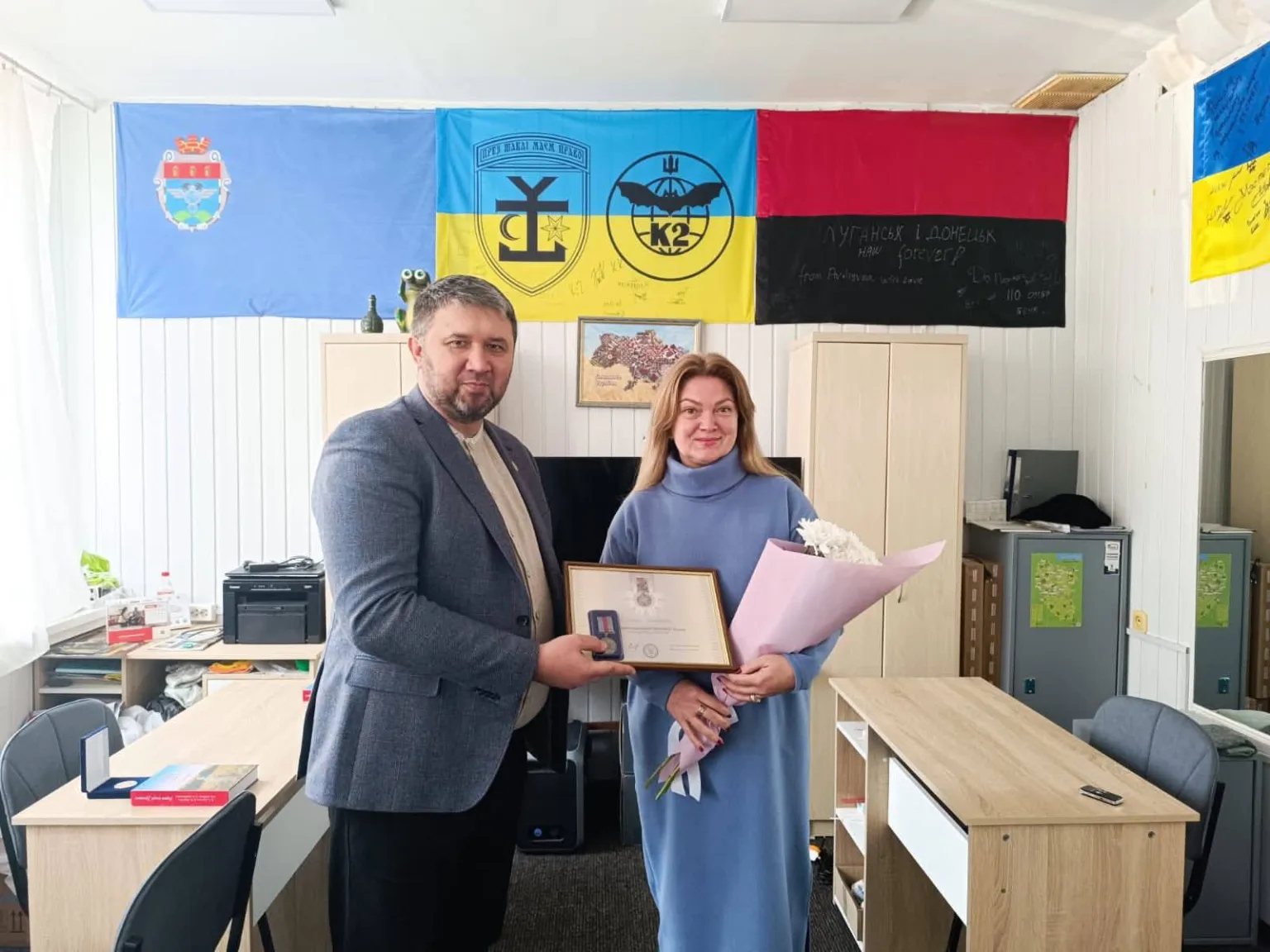 Вручення нагороди жінці в офісі з прапорами