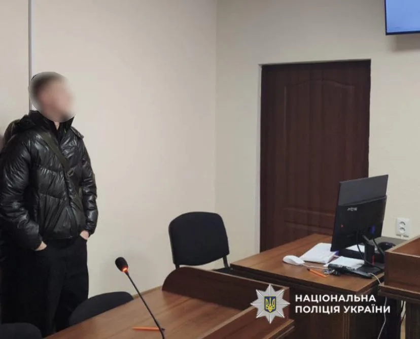 Людина в судовій залі біля столу з комп’ютером