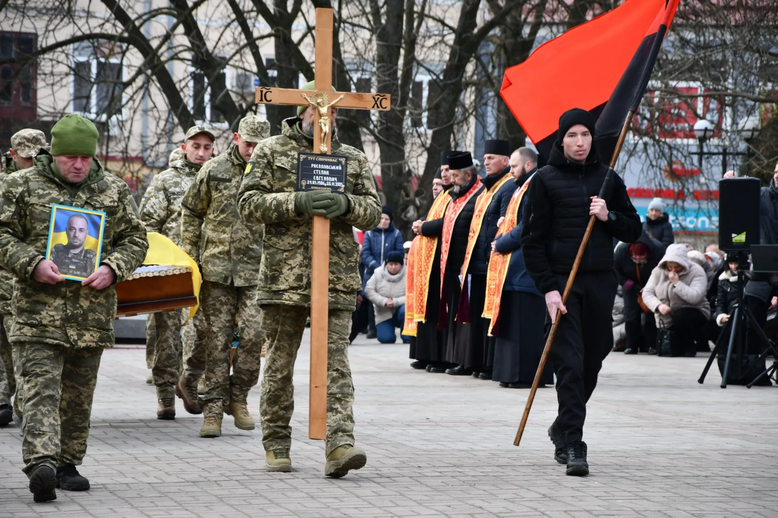 Військовий похорон у місті з прапорами та священниками