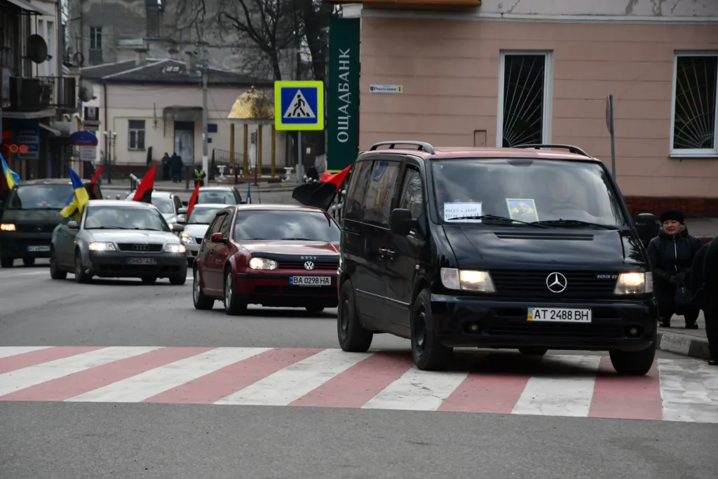 Автоколона з прапорами на міській вулиці