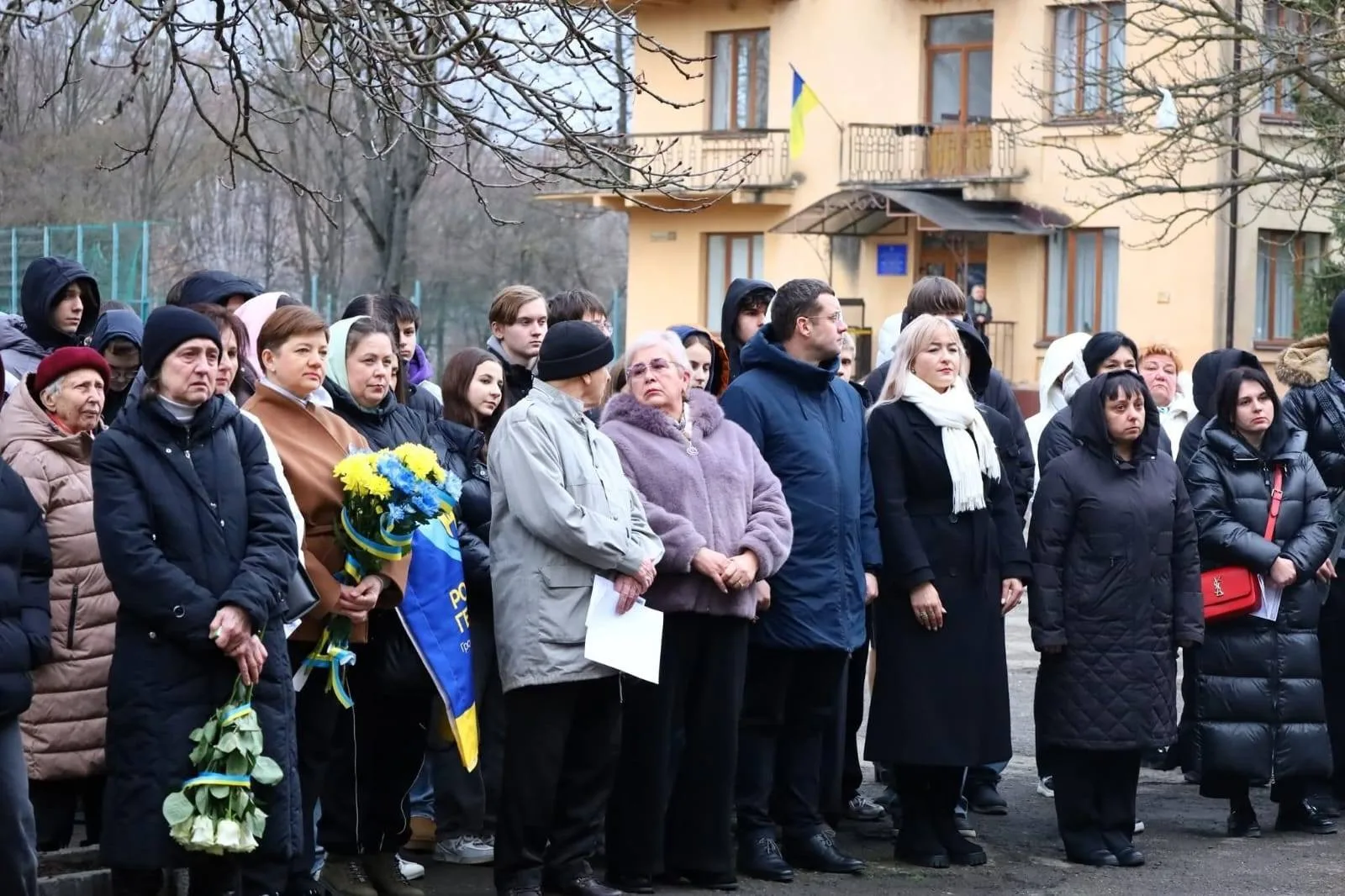 Люди на вуличній церемонії з українським прапором