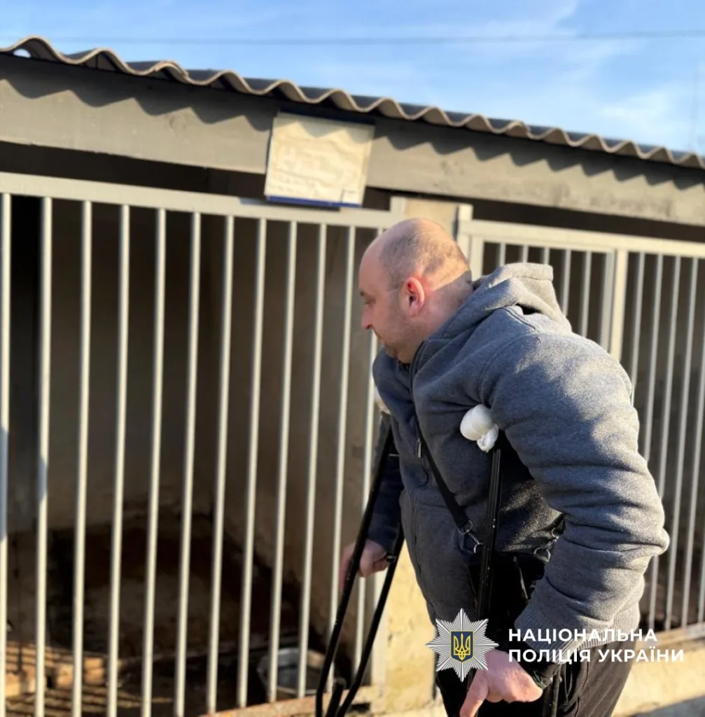 Чоловік на милицях біля клітки в притулку