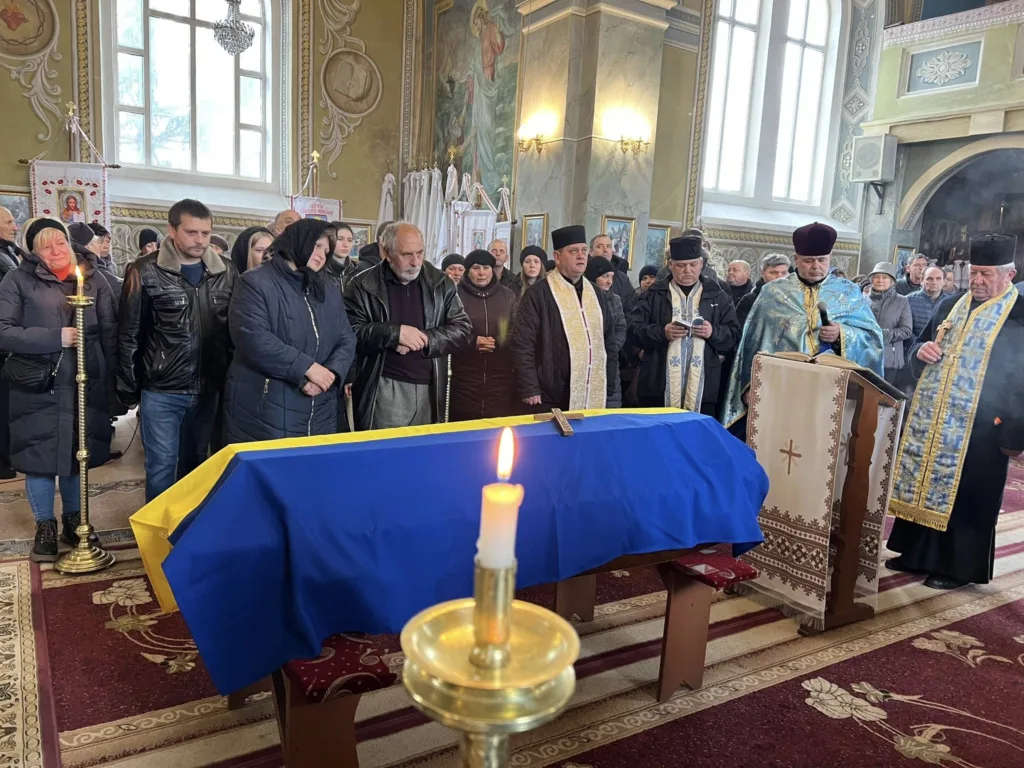 Похорон у церкві з труною в українському прапорі