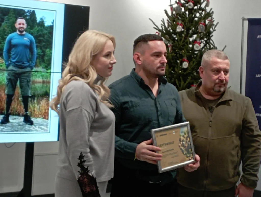 Троє людей отримують сертифікат біля ялинки