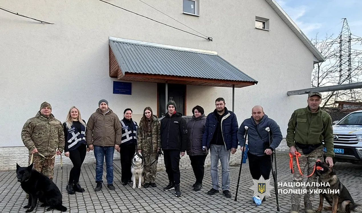 Поліцейські та військові з службовими собаками перед будівлею