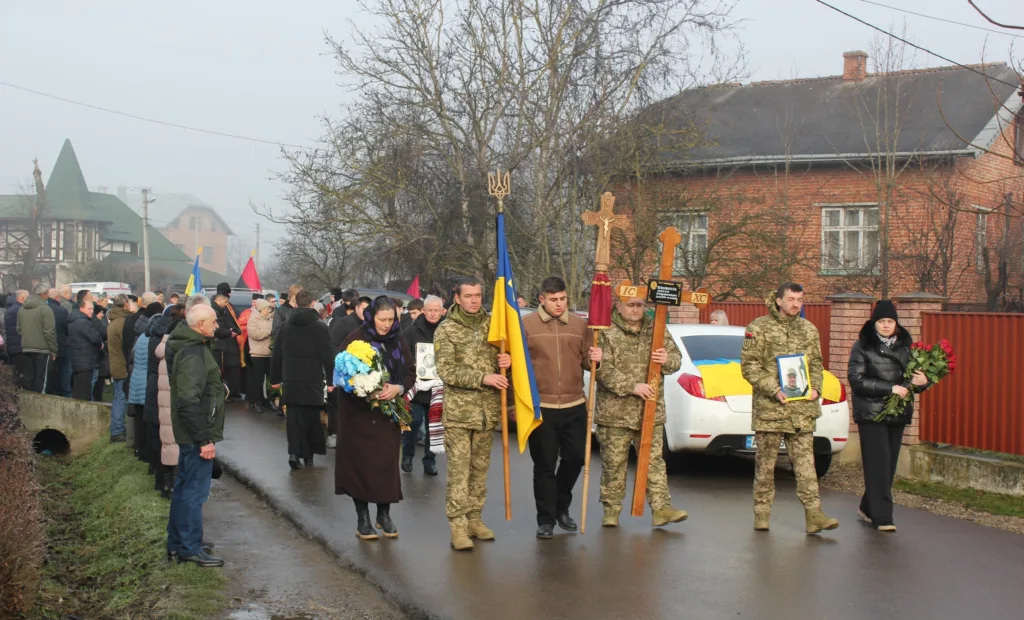 Похоронна процесія з українським прапором у селі
