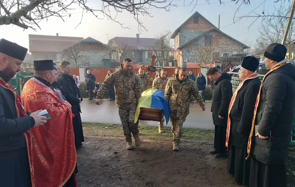 Військові несуть труну, накриту українським прапором