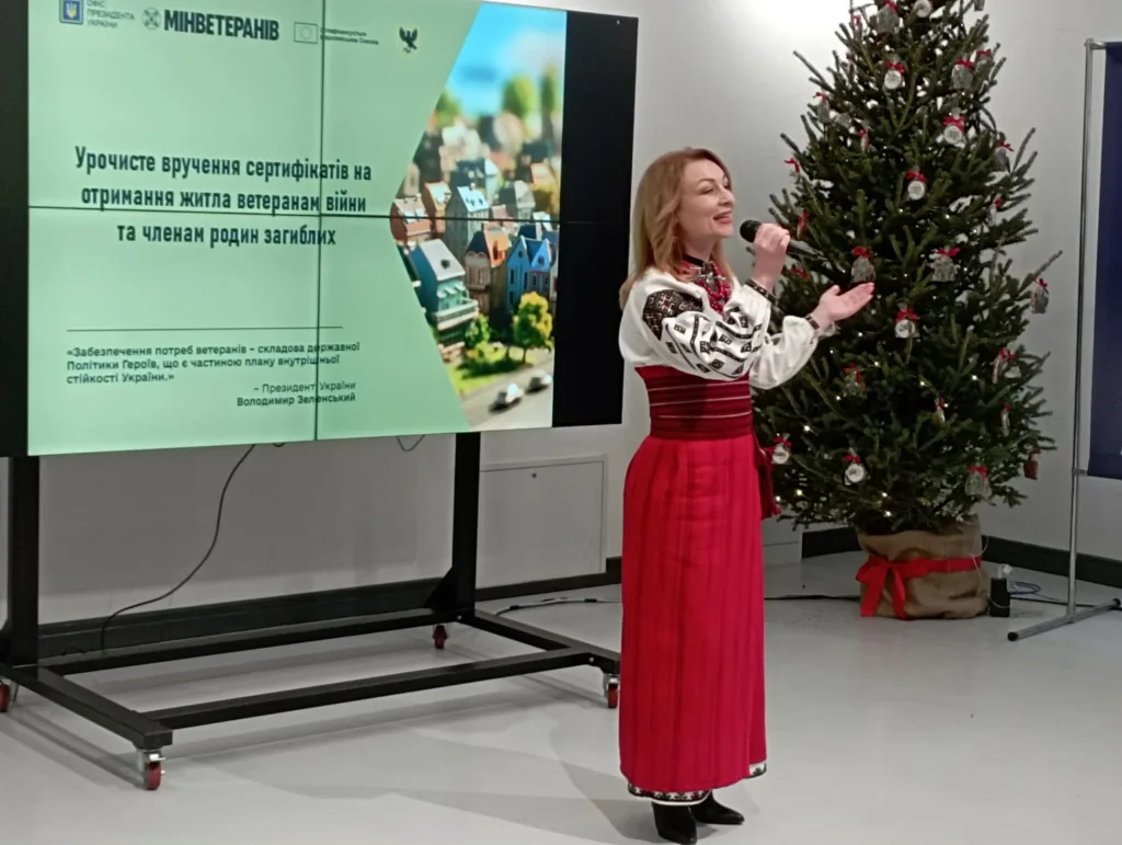 Жінка співає на церемонії вручення сертифікатів ветеранам