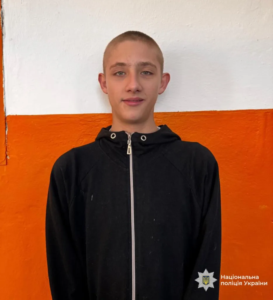 Підліток у чорній кофті перед помаранчевою стіною