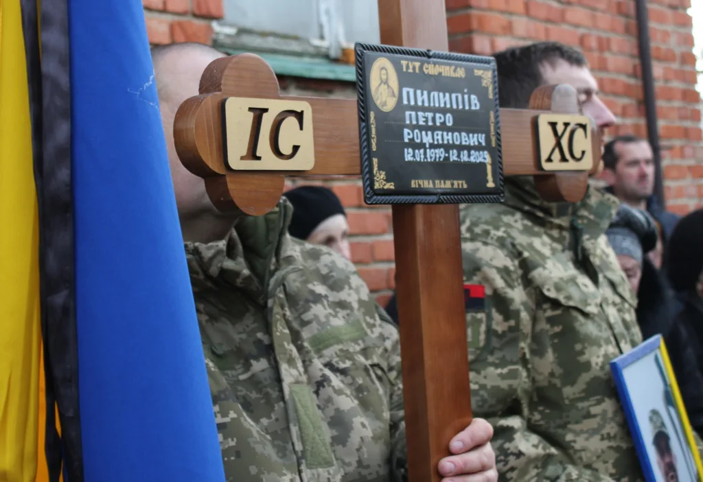 Військові тримають похоронний хрест із прапором України
