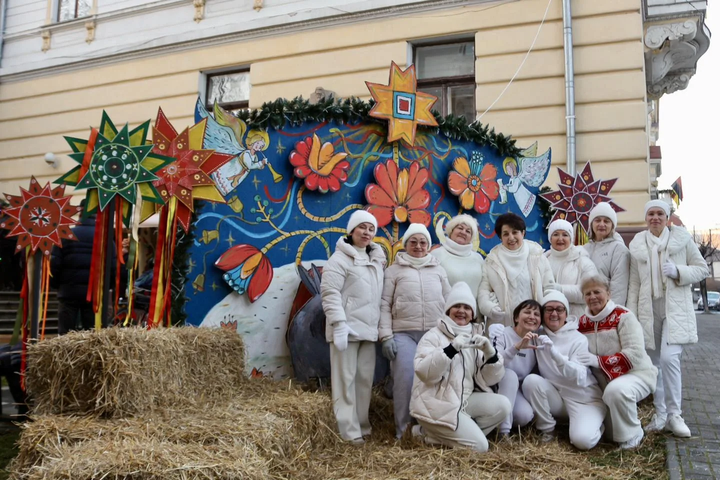 Група людей у білих одежах біля різдвяної декорації