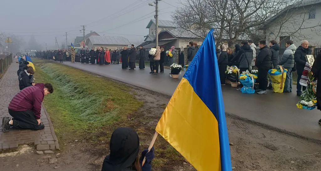 Прощання селян із воїном під українським прапором