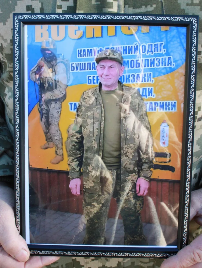 Військовий у камуфляжі тримає фотографію солдата