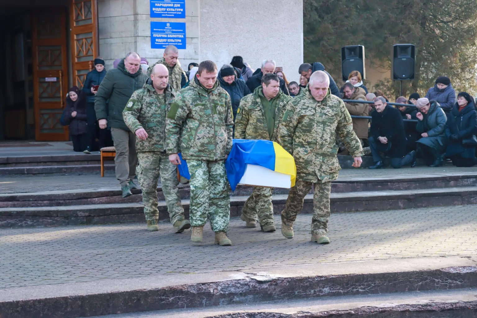 Військові несуть труну, накриту прапором України
