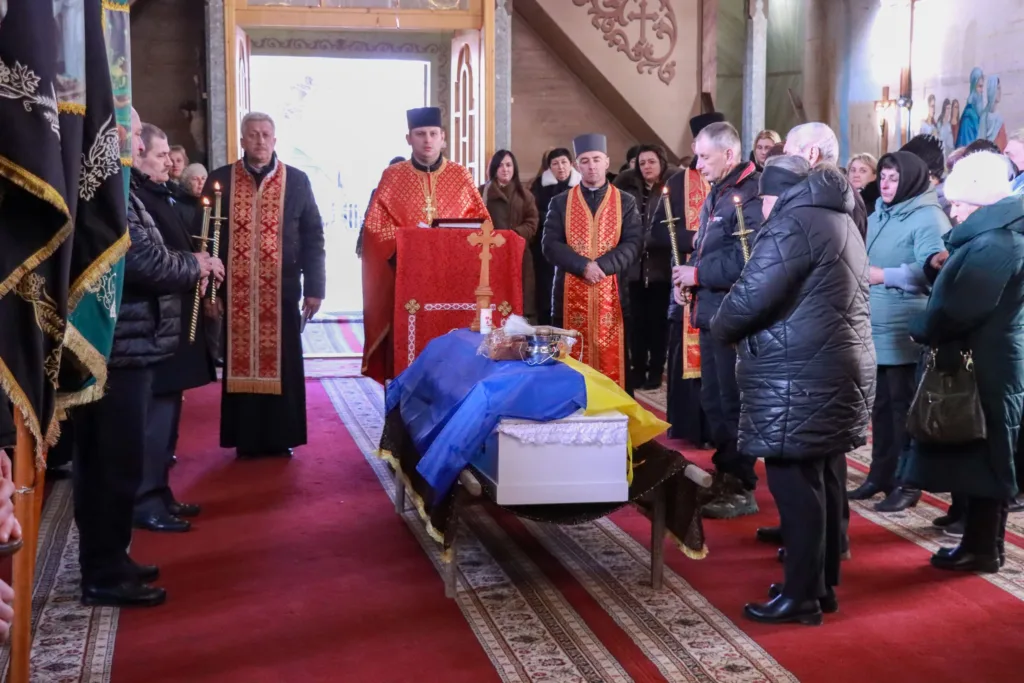 Похоронна церемонія у церкві з українським прапором