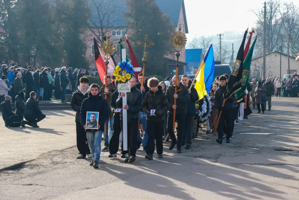 Похоронна процесія з українськими прапорами на вулиці