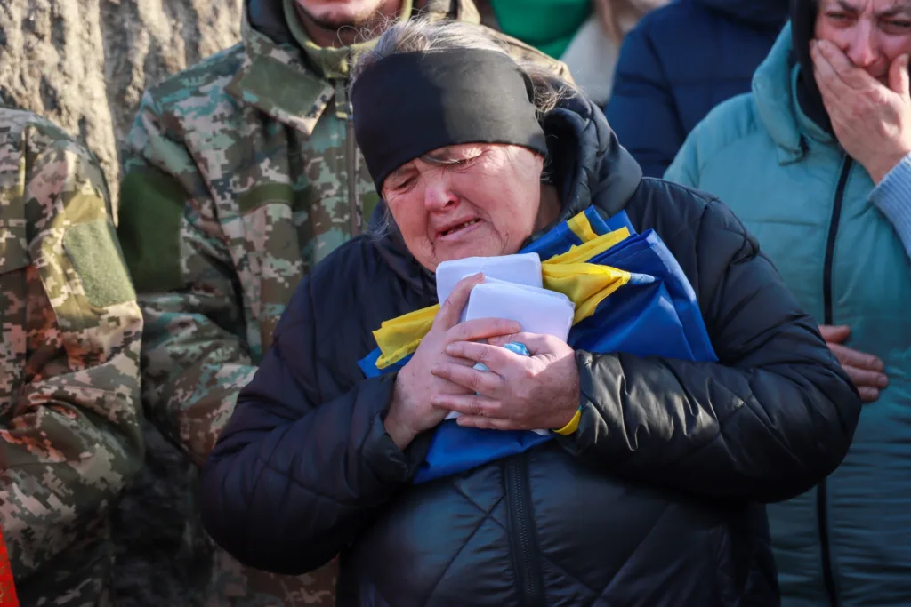 Заплакана жінка тримає український прапор на церемонії