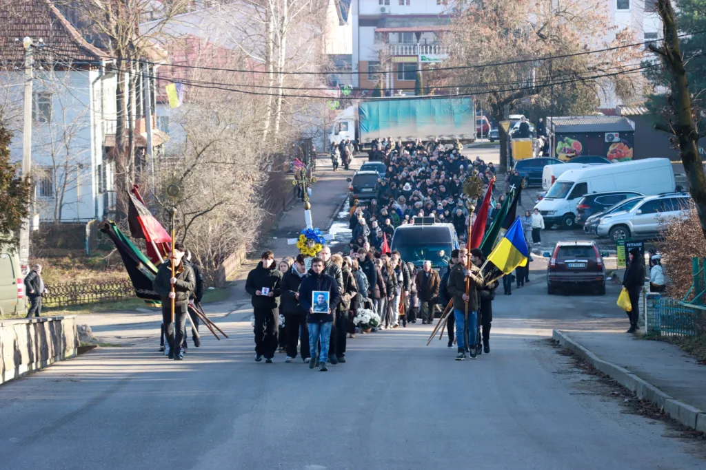 Похоронна процесія з українськими прапорами на вулиці