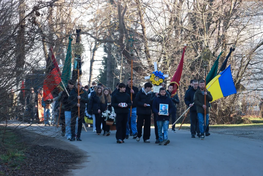 Похоронна процесія з українськими прапорами та квітами