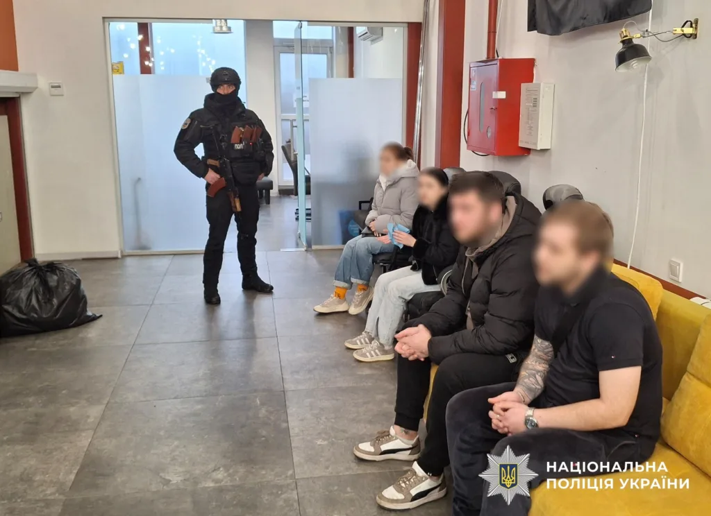 Поліцейський охороняє затриманих у приміщенні