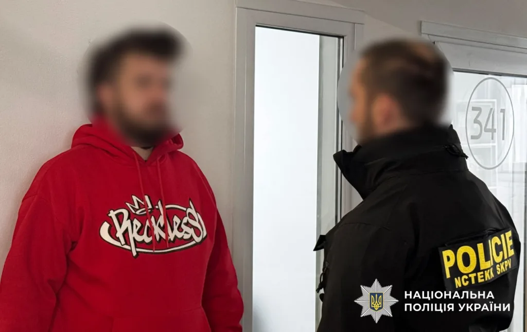 Поліцейський спілкується з чоловіком у червоній худі