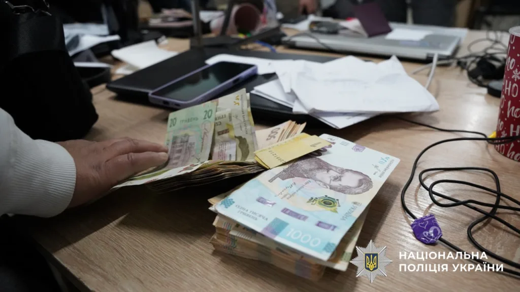 Людина рахує українські гривні на столі